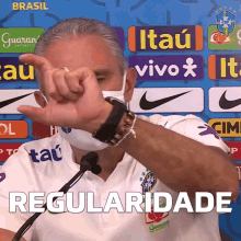 a man wearing a face mask is giving a thumbs up sign in front of a sign that says brasil