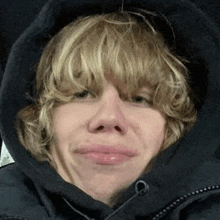 a close up of a person wearing a hooded jacket making a funny face .