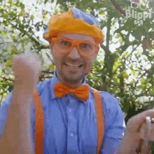 a man in a clown costume with glasses , suspenders and a bow tie is giving a thumbs up .