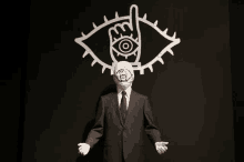 a man in a suit and tie is standing in front of a drawing of an eye