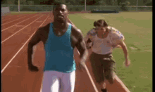 a man and a woman are running on a track . the man is wearing a blue tank top .