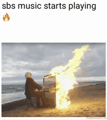 a man playing a piano on a beach with fire coming out of it