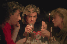 a man holds a glass of wine while talking to two women