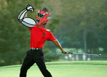 a man in a red shirt and black pants holds a golf club