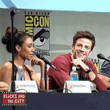 a man and a woman are sitting at a table with microphones in front of them .