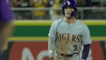 a baseball player wearing a tigers jersey and helmet is standing on a baseball field .