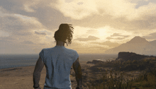 a man with dreadlocks stands in front of a sunset