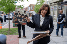 a woman in a suit holds up a one direction record