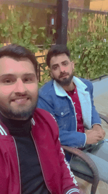 two men are posing for a picture with one wearing a jacket that says adidas on the sleeves