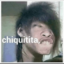 a man with long black hair is making a funny face with the words chiquitita written on his face .