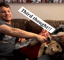 a man sitting on a couch with a dog and a sign that says " third thought "