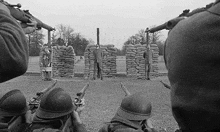 a black and white photo of a group of soldiers holding guns in front of a pile of sandbags .