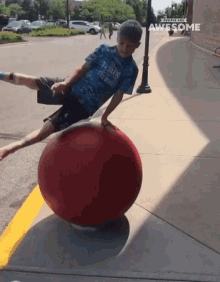 a boy in a blue shirt is balancing on a red ball with the words people are awesome above him