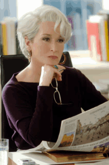 a woman sits at a desk reading a newspaper which says international life