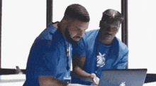 two men are looking at a laptop computer .