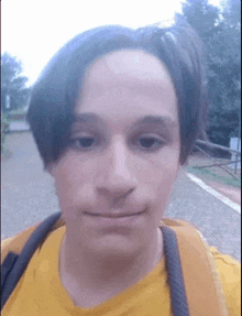 a close up of a person 's face with a yellow shirt and a backpack .