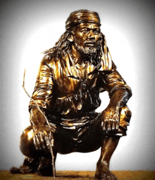 a bronze statue of a man with a beard is squatting down