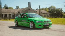 a green bmw is parked on the side of the road