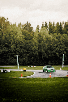 a green car is driving down a track with a sign that says ' bmw ' on it