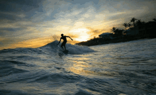 a person riding a wave in the ocean at sunset