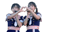 two girls are making a heart shape with their hands and one has a microphone in her mouth