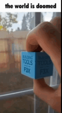 a person is holding a blue cube that says building tools on it