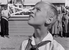 a boy in a striped shirt and tie is looking up in a black and white photo taken by alex uyutov