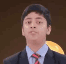 a young boy wearing a suit and tie is standing in front of a hard hat .