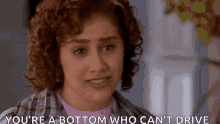 a woman with curly hair is making a funny face and saying `` you 're a bottom who can 't drive ''