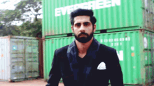 a man with a beard is standing in front of a green container that says evergreen