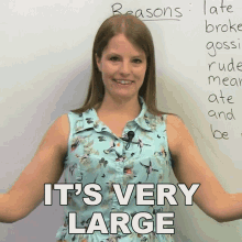 a woman stands in front of a white board with the words " it 's very large " on it