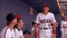 a group of baseball players are standing in a dugout and one of them is wearing a jersey that says indians