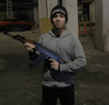 a man holding a gun wearing a beanie that says diesel inc.