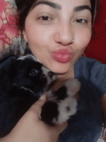 a woman is holding a small black and white dog in her arms