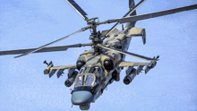 a military helicopter is flying in the sky with missiles attached to it