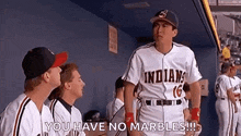 a group of baseball players are standing in a dugout and one of them is wearing an indians jersey .