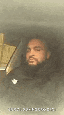 a man with a beard is sitting in the back seat of a car and looking at the camera .