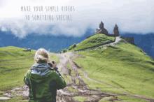 a woman taking a picture of a castle on top of a hill