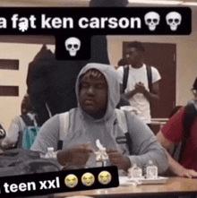 a man in a hoodie sits at a table with a caption that says a fat ken carson teen xxl