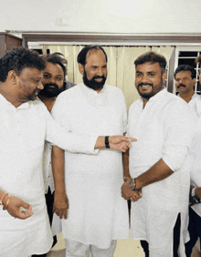 a group of men in white shirts are shaking hands and smiling