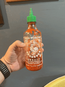 a bottle of sriracha hot chili sauce is being held by a person