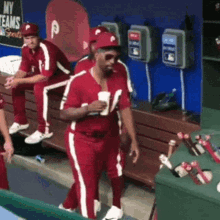 a group of baseball players are sitting on a bench in a dugout with a sign that says my teams