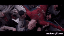 a man in a spiderman costume is being held up by people