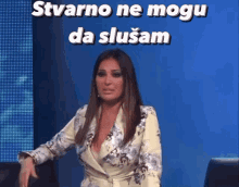 a woman is sitting in front of a blue wall with the words " stvarno ne mogu da slusam " on it