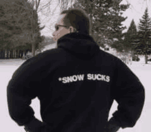 a man is wearing a black hoodie that says `` snow sucks '' .