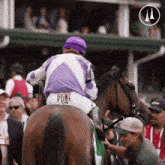 a jockey wearing a purple jacket that says pdaf on the back of it