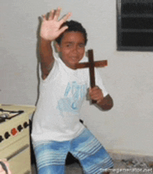 a young boy is holding a wooden cross in his hand