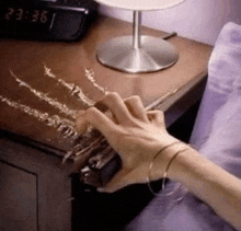 a person 's hand is scratching a piece of wood on a table .