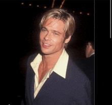 a man wearing a blue jacket and a yellow shirt smiles for the camera