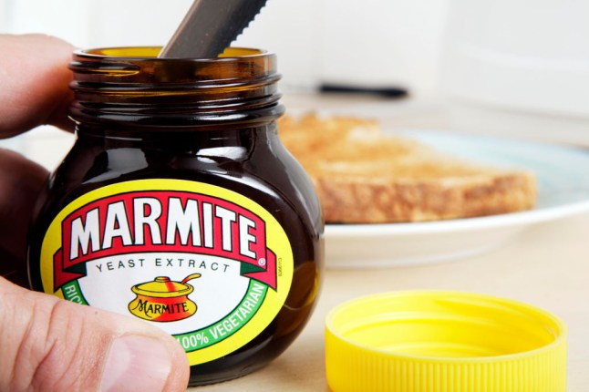 A man getting Marmite out of the jar with a knife.